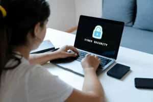 Mujer utilizando un ordenador vista desde atras con la palabra ciberseguridad en la pantalla del ordenador