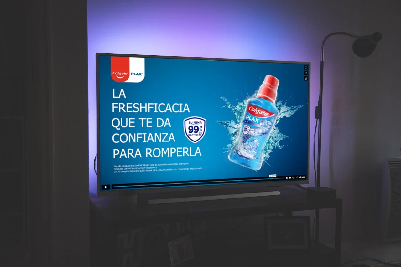 Mesa con un televisor en el que se esta viendo un anuncio de colgate